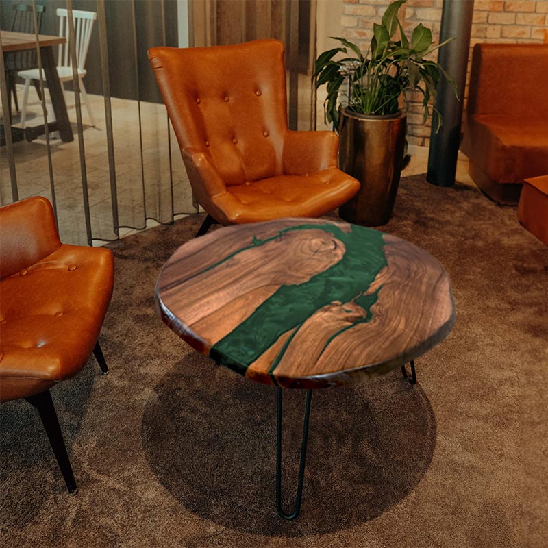 Couchtisch rund mit Naturkanten aus Nussbaum & Epoxidharz in grün, in gemütlichem Setting mit zwei braunen Ledersesseln. Modell Titisee von schwarzhirsch