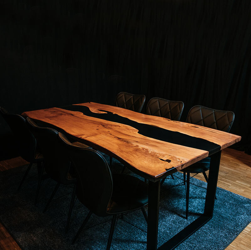 Epoxidharz Tisch aus Esche mit 6 schwarzen Stühlen auf blauem Teppich. Modell Hirschsprung von Schwarzhirsch