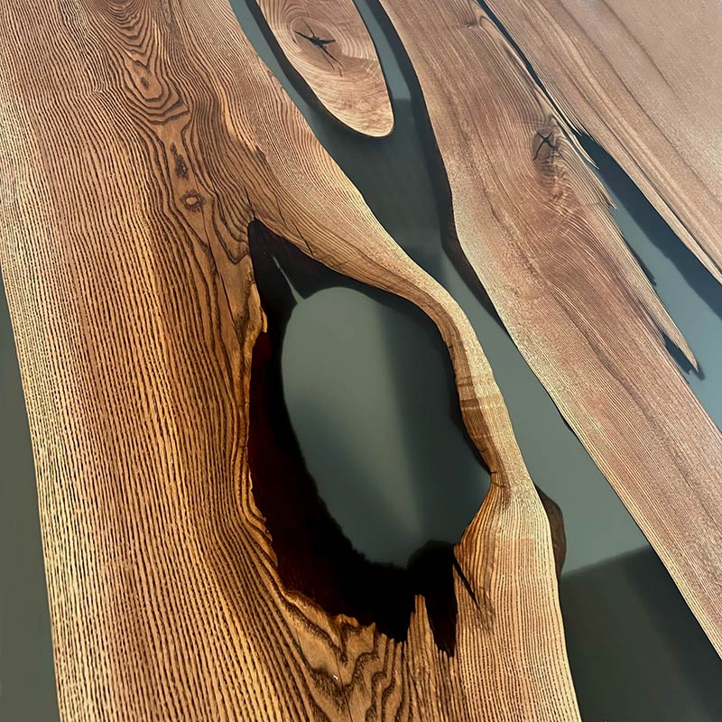 River Table. Detailbild Oberfläche von Epoxidharz Tisch aus Nussbaum mit grauem Epoxidharz. Modell Eichhörnchen mit X-Gestell von Schwarzhirsch