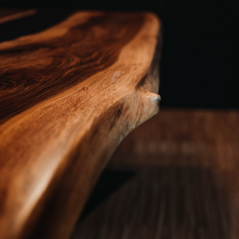 Tisch Epoxidharz. Detailbild der natürlichen Baumkante von Epoxidharz Tisch aus Nussbaum mit anthrazitfarbenem Epoxidharz. Modell Schwarzwälder Kirsch von schwarzhirsch