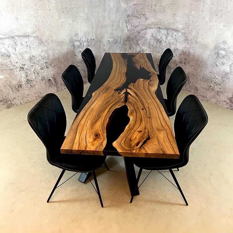 Epoxy Tisch. Bestuhlter Esstisch Holz mit schwarzem Epoxidharz und X-Gestell. Modell Wildsee