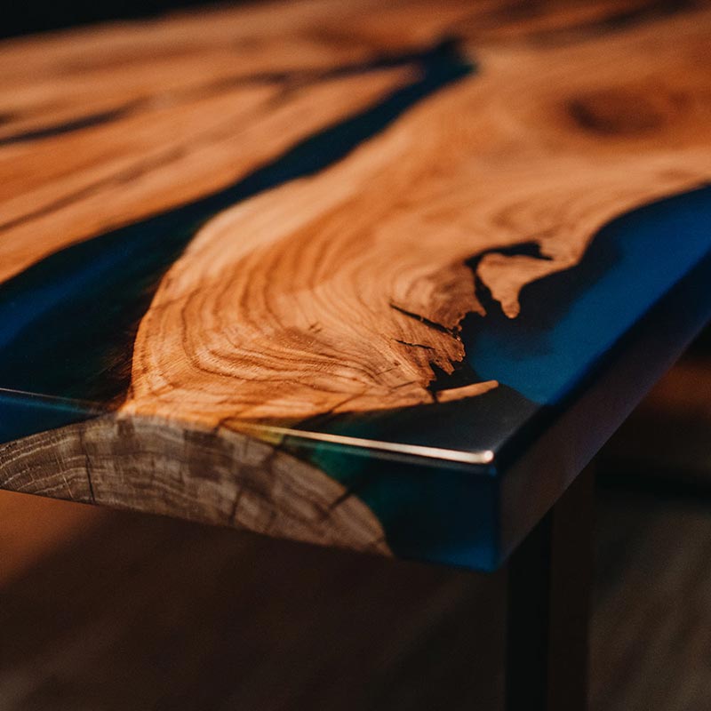 Tisch Epoxidharz. Detailbild gerade Tischkante. Epoxidharz Tisch aus rustikaler Eiche mit blauem Epoxidharz. Modell Adria von schwarzhirsch