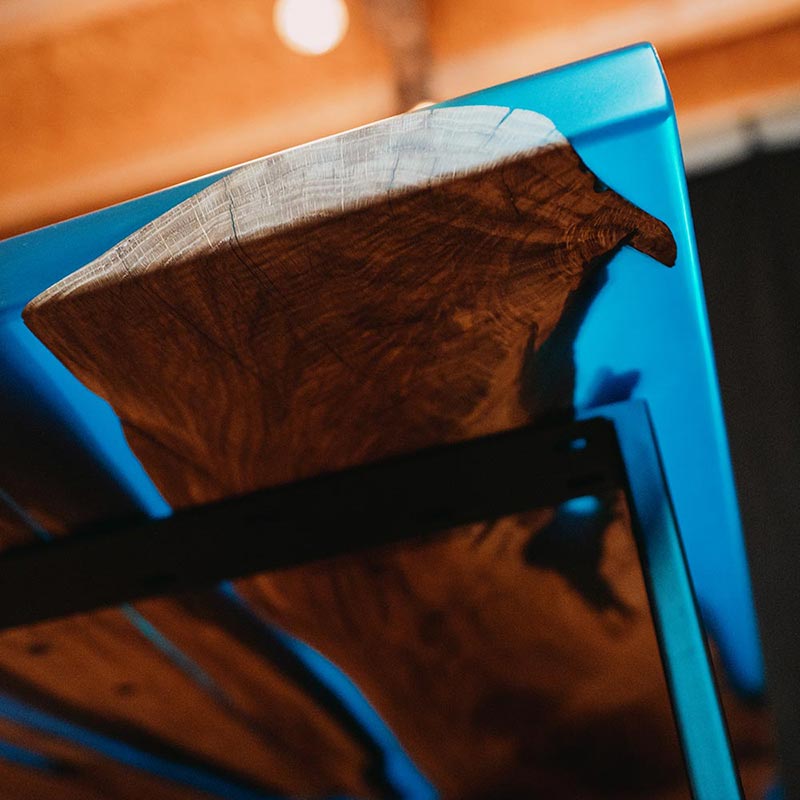 Detailbild gerade Tischkante von unten Fotografiert. Epoxidharz Tisch aus rustikaler Eiche mit blauem Epoxidharz. Modell Adria von schwarzhirsch
