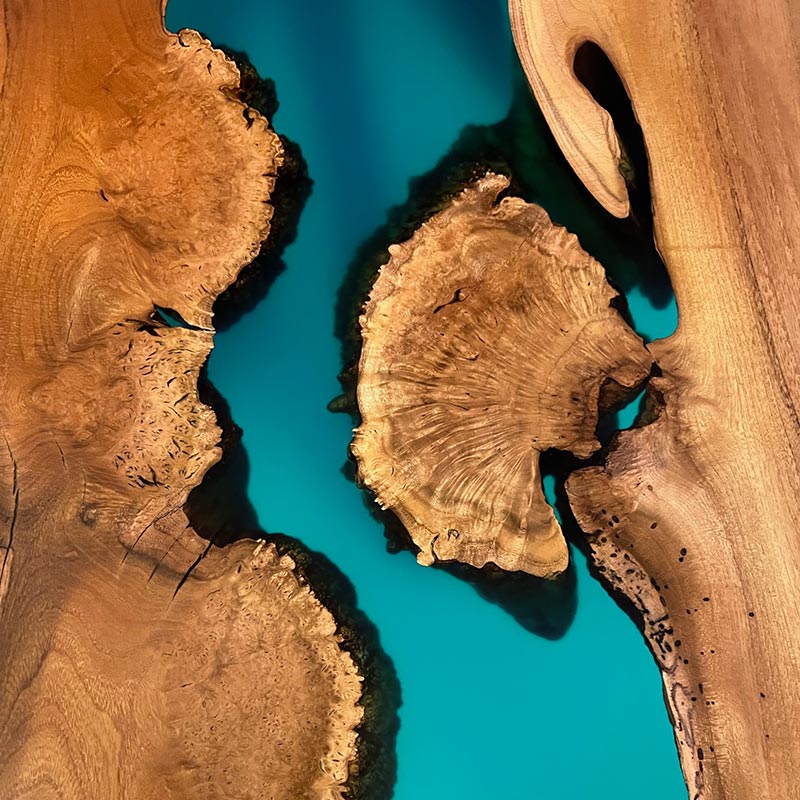 Detailbild Oberfläche mit türkis-blauem Epoxidharz an natürlicher Baumkante von Epoxidharz Tisch aus Akazie mit Kreuzgestell. Modell Gletschersee von Schwarzhirsch