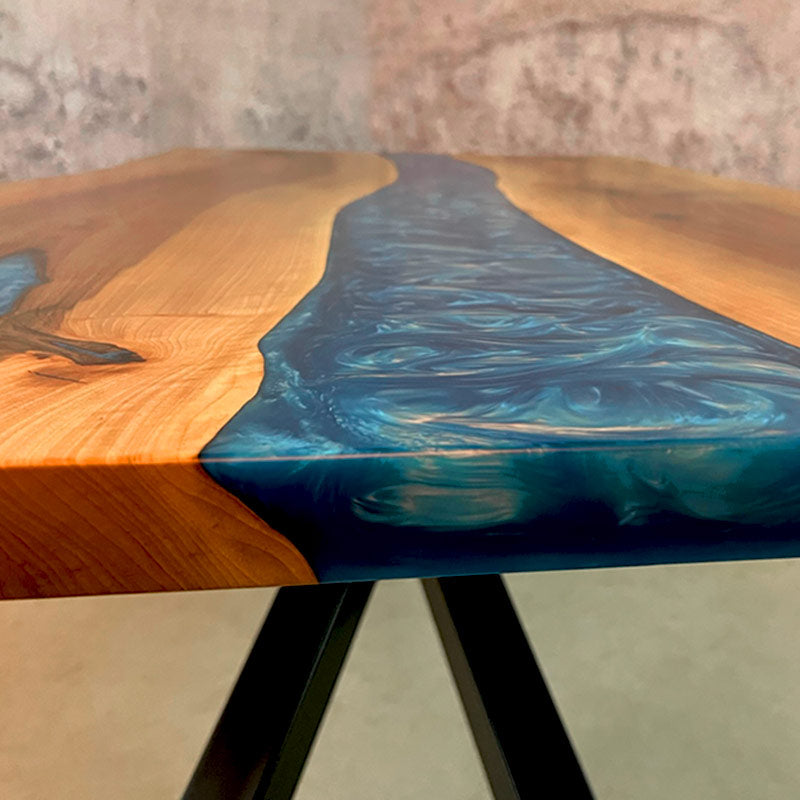 Detailbild Tischkante. Oberfläche und Farbverlauf von Epoxidharz Tisch aus Nussbaum mit blau pigmentiertem Epoxidharz. Modell Kinzig mit Kreuzgestell von Schwarzhirsch