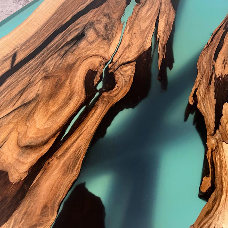 Detailbild Oberfläche River Table Nussbaum mit türkisem Epoxidharz und X-Gestell. Modell Schluchsee von schwarzhirsch
