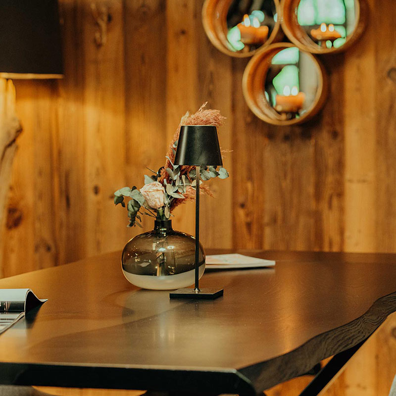 Esstisch aus schwarzer Eiche mit weißem Epoxidharz. Der Tisch ist dekoriert mit einer Vase mit Trockenblumen und einer schwarzen Tischlampe. Modell Blackforest von Schwarzhirsch.