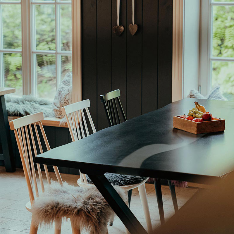 Esstisch schwarze Eiche mit weißem Epoxidharz. Der Tisch ist dekoriert und gesäumt von 6 Stühlen. Modell Blackforest von Schwarzhirsch.